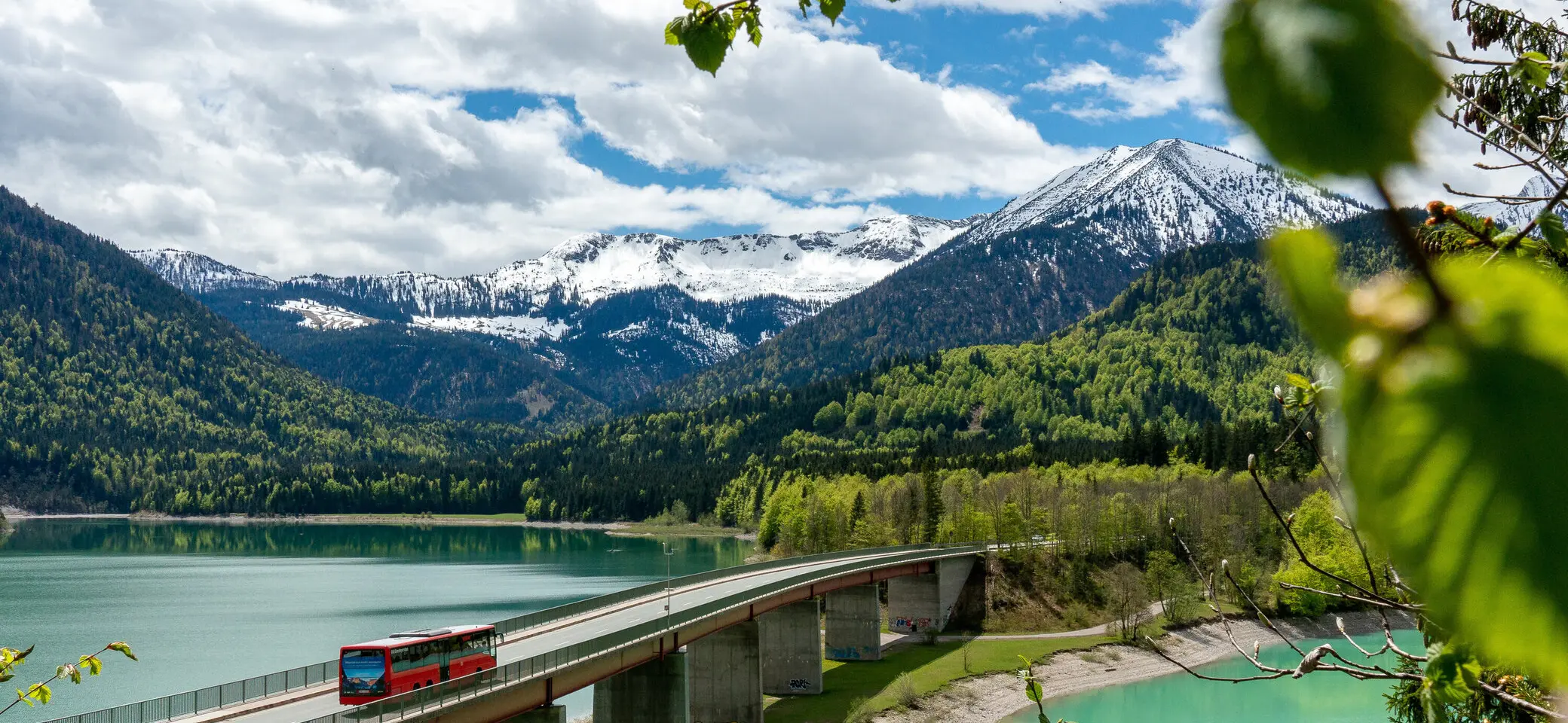Der Bergbus des Deutschen Alpemvereins fährt über eine Brücke in die Alpen | © DAV/Tobias Hipp