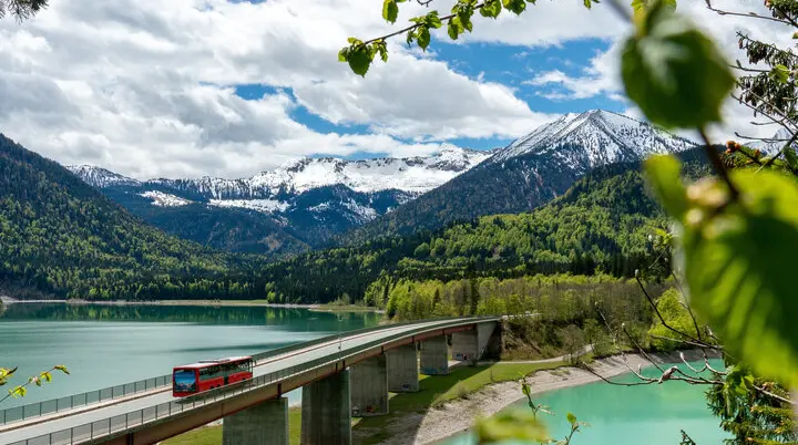Der Bergbus des Deutschen Alpemvereins fährt über eine Brücke in die Alpen | © DAV/Tobias Hipp